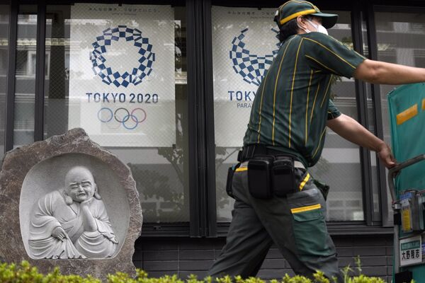 東京五輪・パラリンピックのポスター前を通り過ぎる配達員 - Sputnik 日本