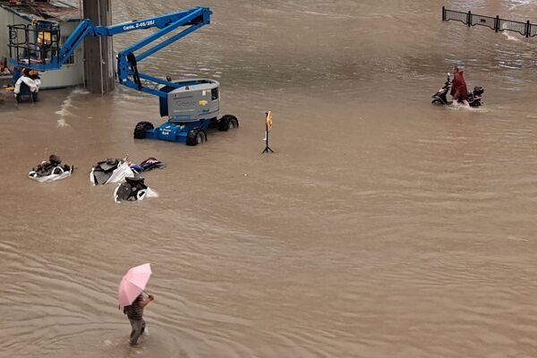 河南省の州都・鄭州市で、水をかき分けて道路を歩く市民ら - Sputnik 日本