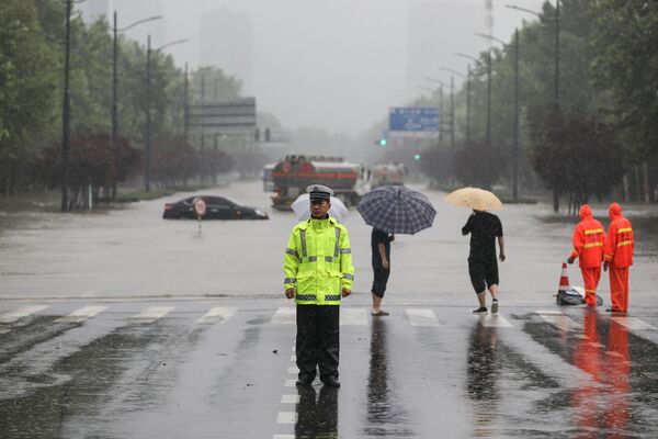 河南省の州都・鄭州市で、冠水した道路の前で警備にあたる警察官 - Sputnik 日本