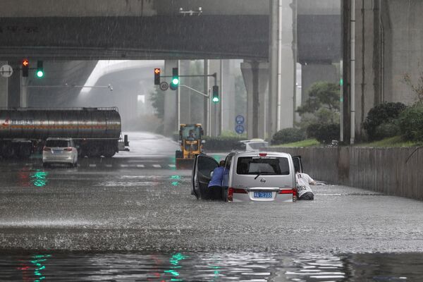 河南省の州都・鄭州市で、冠水した道路で車を押す市民ら - Sputnik 日本