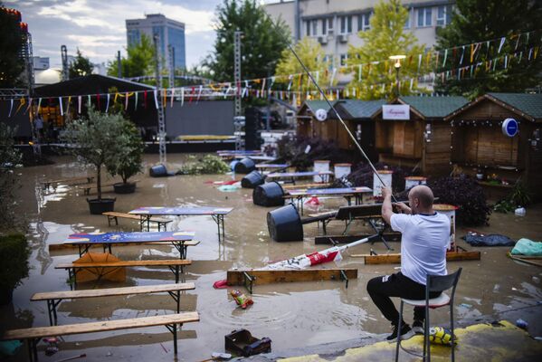 コソボ首都・プリシュティナで、洪水の被害を受けた広場で釣り竿を持つ男性  - Sputnik 日本