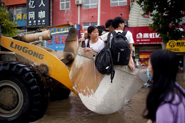 中国・河南省鄭州市で、大雨により冠水した道路をホイールローダーに乗って進む市民ら - Sputnik 日本