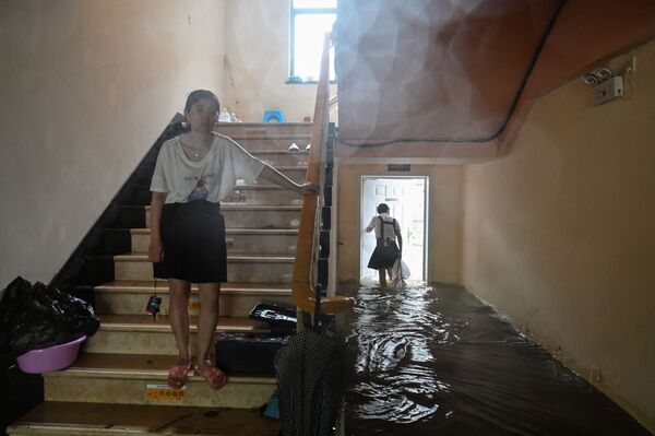 中国・浙江省寧波市で、台風によって浸水した建物の階段を下りる住民ら - Sputnik 日本
