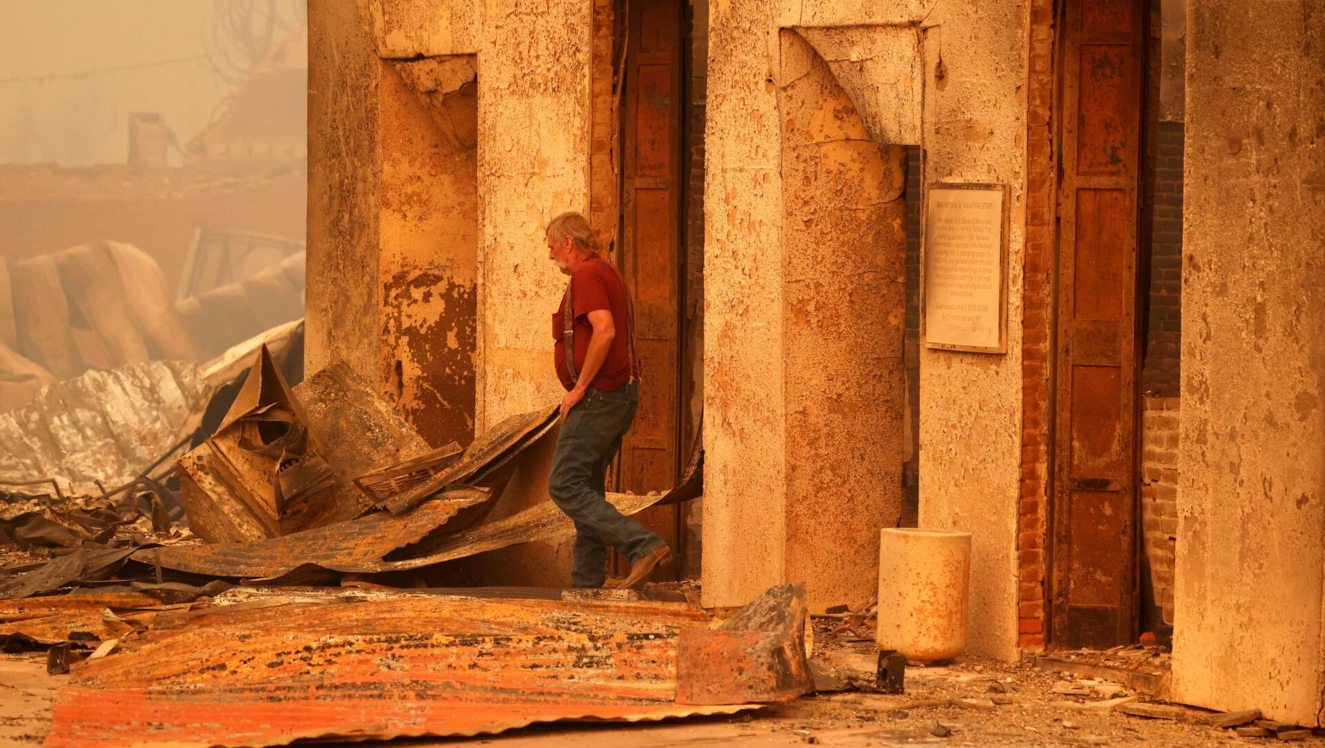 Житель осматривает сгоревшее коммерческое здание, принадлежащее его другу, после пожара, разразившегося в городе Гринвилл, штат Калифорния - Sputnik 日本, 1920, 08.08.2021