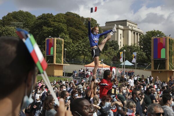 フランス・パリのトロカデロ庭園に設置されたパリ五輪のファンゾーンで、フランス国旗を持ってアクロバットを披露する女性 - Sputnik 日本
