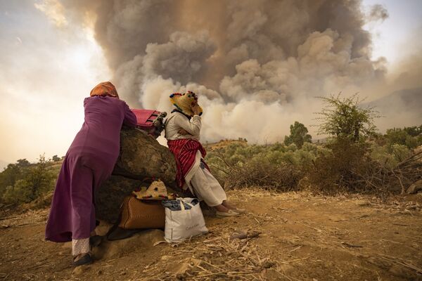 モロッコ・シャウエンで、森林火災が発生する中、荷物を持って山中に佇む女性ら - Sputnik 日本