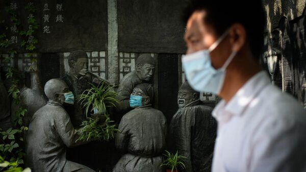 北京のレストランの前で仮面をつけた彫刻の前を歩く男性 - Sputnik 日本