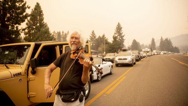 米カリフォルニア州サウスレイクタホで、森林火災「カルドー・ファイア」から避難する住民が渋滞を作っている中、バイオリンを弾く男性 - Sputnik 日本