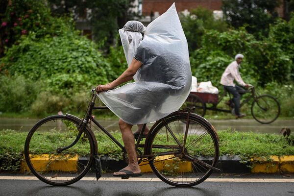 インド・ファリダバードで、豪雨の中、ビニールで体を覆って走る男性 - Sputnik 日本