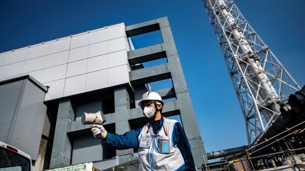 Специалист проверяет уровень радиации с помощью дозиметра рядом с зданием реактора на атомной электростанции Фукусима - Sputnik 日本