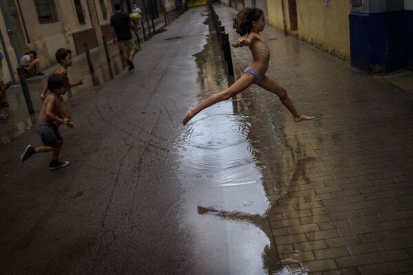 スペイン・バルセロナで水たまりを飛び越える子ども - Sputnik 日本