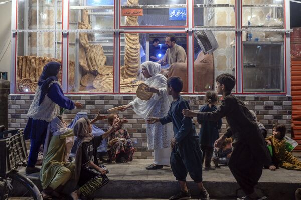 アフガニスタン・カブールで、パン屋の前で子どもたちにパンを分ける女性 - Sputnik 日本
