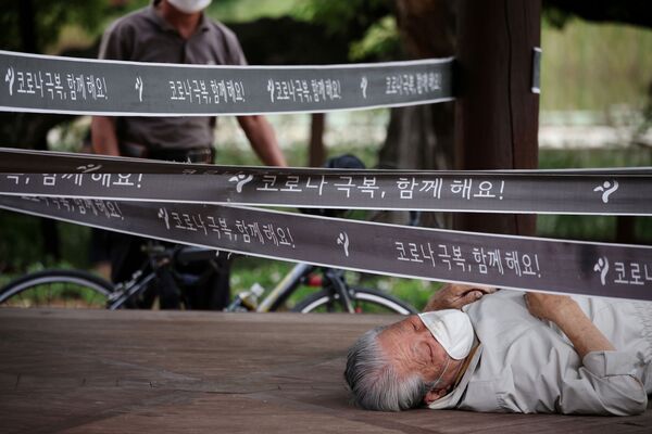 韓国・ソウルで、新型コロナウイルスの感染対策で封鎖された公園で寝そべる男性 - Sputnik 日本