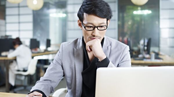 Азиатский мужчина за ноутбуком в офисе  - Sputnik 日本