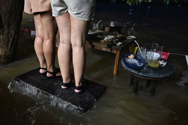 タイ中部・ノンタブリー県で、水浸しになったレストラン「Chaopraya Antique」で椅子に立ちながら食事をする人々 - Sputnik 日本