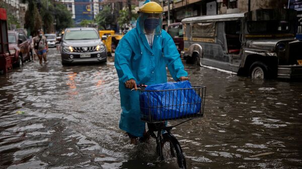 Мужчина в маске едет на велосипеде по затопленной улице в Маниле, Филиппины - Sputnik 日本