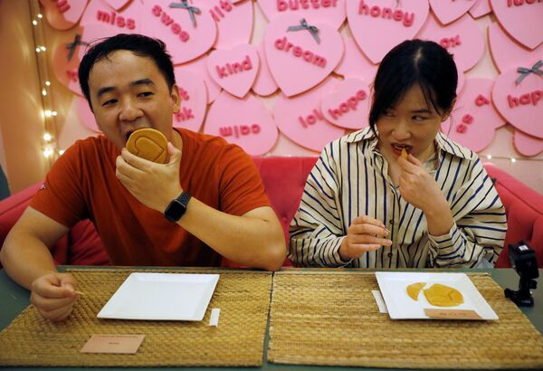 シンガポールのカフェで、『イカゲーム』劇中で行われた「ダルゴナ（カルメ焼き）」の型抜きにチャレンジする男女 - Sputnik 日本
