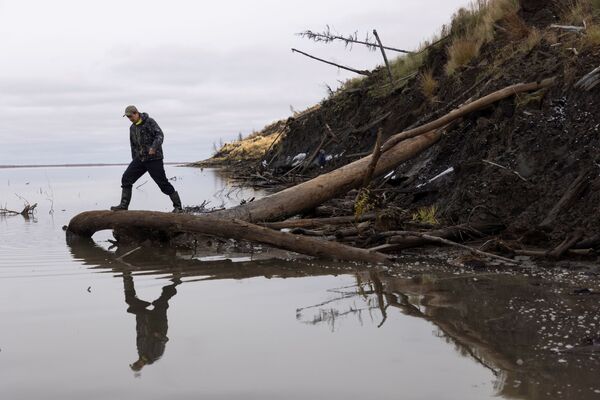 サハ共和国北東部・チェルスキーを流れるコリマ川の土手を歩くセルゲイ・ジモフさんの息子で公園管理者のニキータ・ジモフさん - Sputnik 日本