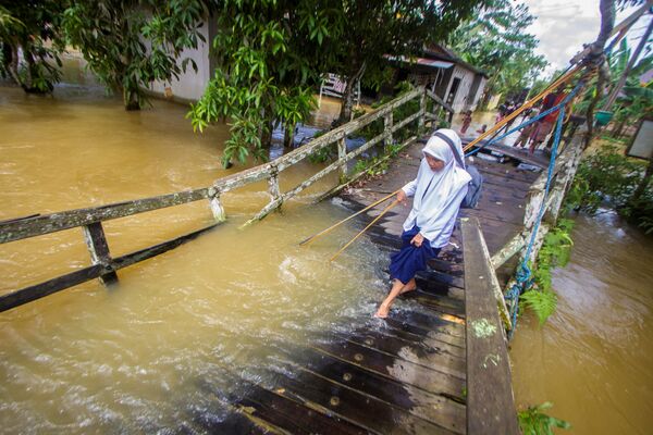 豪雨により氾濫した川の橋をを渡る学生（インドネシア・南カリマンタン県、17日） - Sputnik 日本