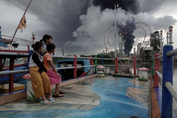 大規模な火災が発生した製油所から上がる黒煙を眺める子どもたち（インドネシア・中部ジャワ州、14日） - Sputnik 日本