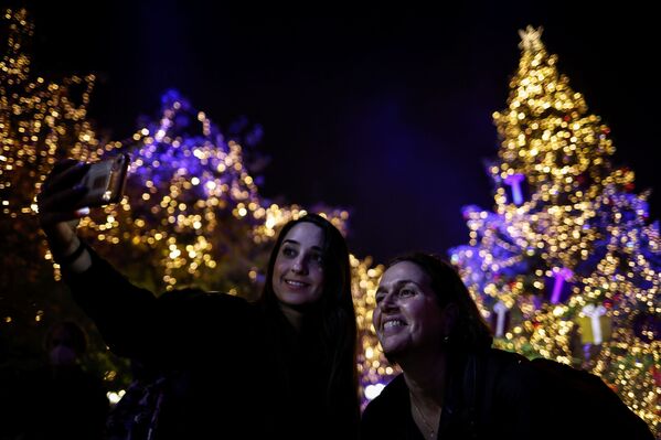 クリスマスツリーの点灯式でセルフィーを撮る女性（ギリシャ・アテネ、23日） - Sputnik 日本