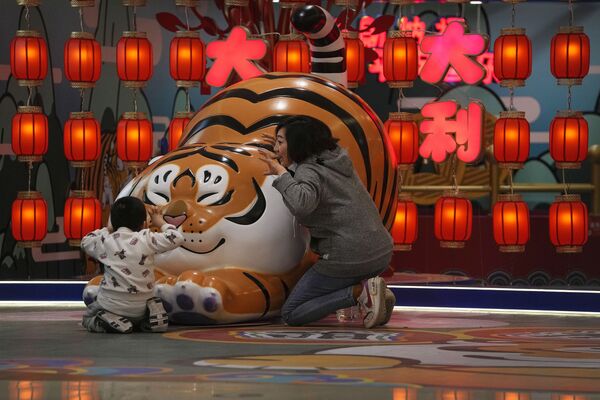 春節を前に飾られたトラの置き物の前でポーズをとる親子（中国・北京、9日）  - Sputnik 日本