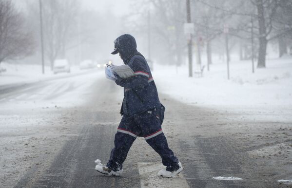 雪が積もる道路を渡る郵便配達員（米コロラド州・デンバー、25日） - Sputnik 日本