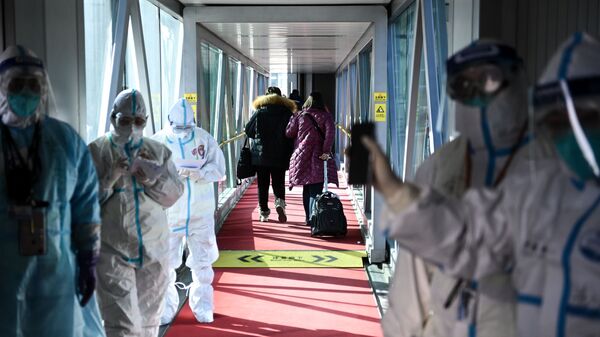 Медицинские сотрудники в защитных костюмах на телескопическом трапе в аэропорту Шоуду в Пекине - Sputnik 日本