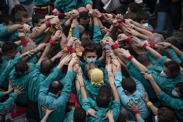 「サンタ・エウラリア祭」で、人間の塔を作るため手を合わせる参加者ら（スペイン・バルセロナ、11日） - Sputnik 日本