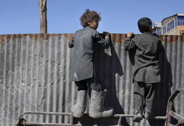 食糧を受け取る人々を壁越しに眺める少年ら（アフガニスタン・カブール、16日） - Sputnik 日本