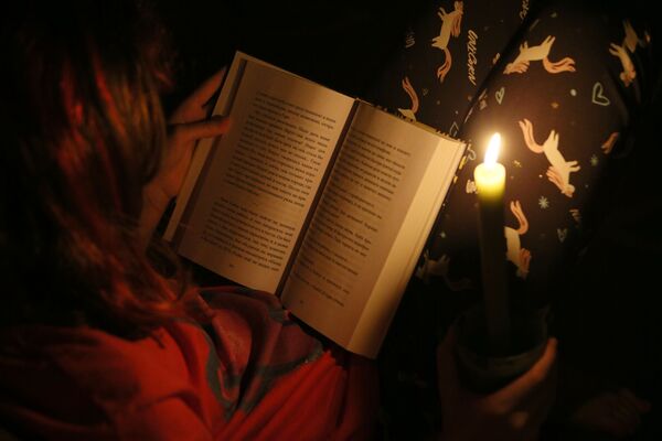 試験的に行われた停電中、ろうそくの明かりで読書する子ども - Sputnik 日本