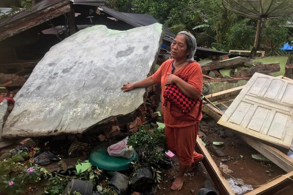 地震で倒壊した家の前に立つ女性（インドネシア・西スマトラ州西パサマン県、25日） - Sputnik 日本
