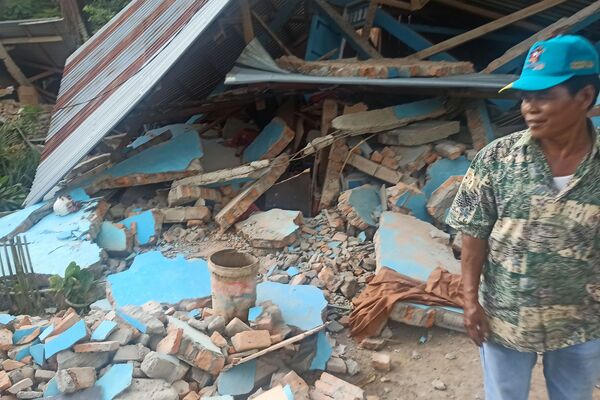 地震で倒壊した家の前に立つ男性（インドネシア・西スマトラ州西パサマン県、25日） - Sputnik 日本