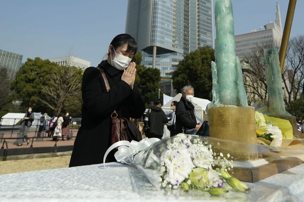 追悼集会で、献花台に花を手向け黙とうをささげる女性（東京都、11日） - Sputnik 日本