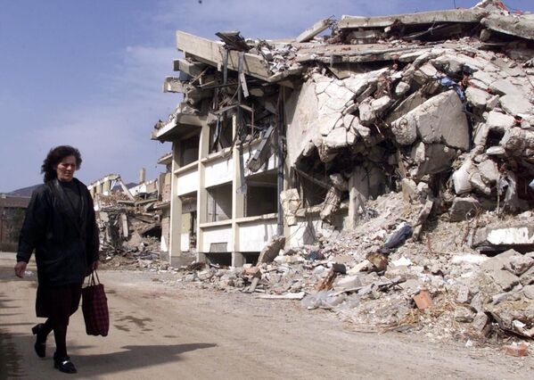 コソフスカ・ミトロビツァで、爆撃を受け崩壊した警察署のそばを通り過ぎる女性（2000年3月25日） - Sputnik 日本