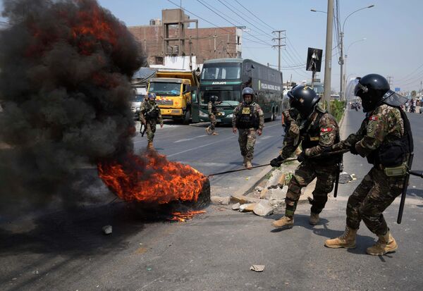 抗議のためトラックやバスで封鎖された中央高速道路から燃えるタイヤを撤去する警察（ペルー・リマ郊外、4日） - Sputnik 日本