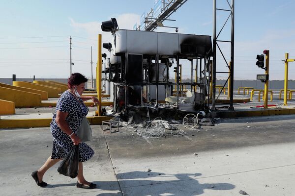 高速料金の値上げに反対するデモで、焼失した料金所の前を歩く女性（ペルー・イカ県イカ市、4日） - Sputnik 日本