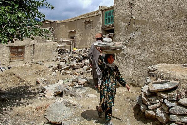 地震で損壊した建物から台所用品を運ぶ子ども（アフガニスタン・パクティカ州、22日） - Sputnik 日本
