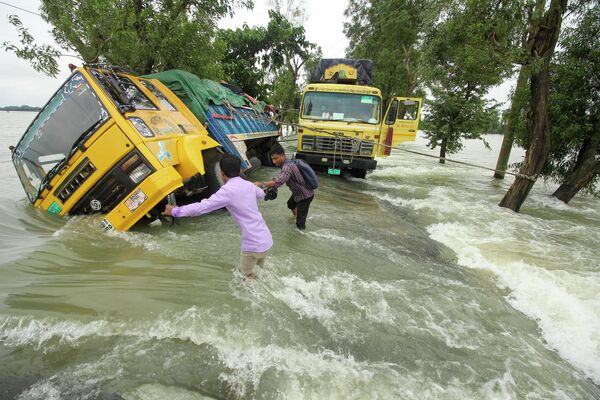 冠水した道路で、立ち往生したトラックのそばを横切る人々（バングラデシュ・スナムガンジ、21日） - Sputnik 日本