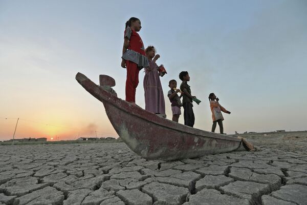 干上がった沼地の底に取り残されたボートの上に立つ子どもたち（イラク・ジーカール県、24日） - Sputnik 日本