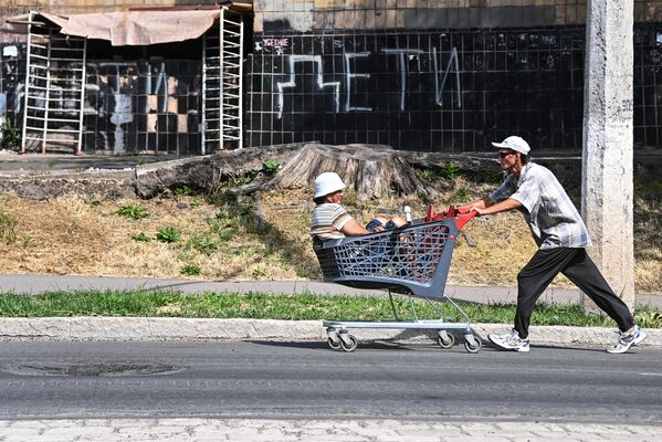 買い物カートに女性を乗せて街を歩く男性（ドネツク人民共和国・マリウポリ、24日） - Sputnik 日本
