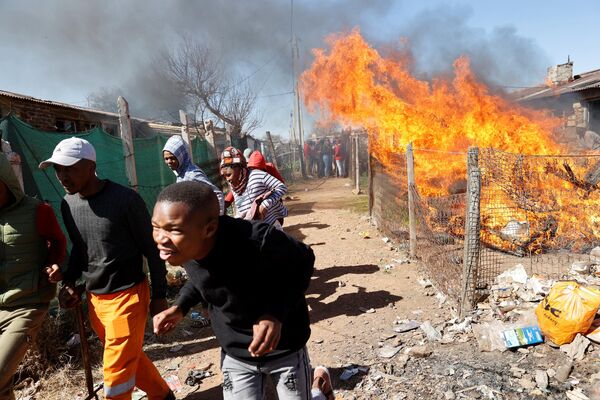 集団レイプ事件に関与したとされる違法採掘者の所持品を燃やす火から逃げ出す住民（南アフリカ・クルーガーズドープ、8日） - Sputnik 日本