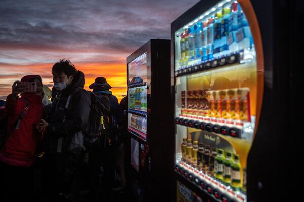 山頂にある自動販売機の横で写真を撮る男女（15日） - Sputnik 日本