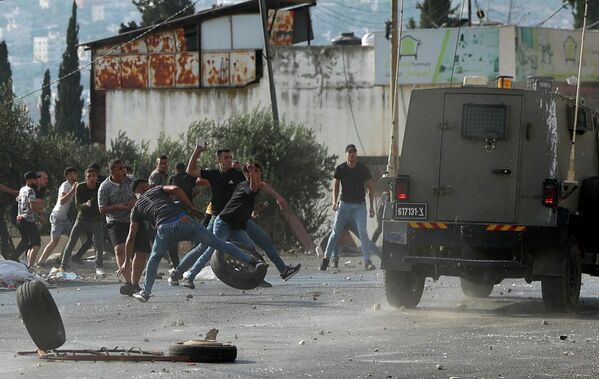 逮捕・襲撃を行うイスラエル軍の車両へ石を投げる若者（パレスチナ自治区・ヨルダン川西岸地区、17日） - Sputnik 日本
