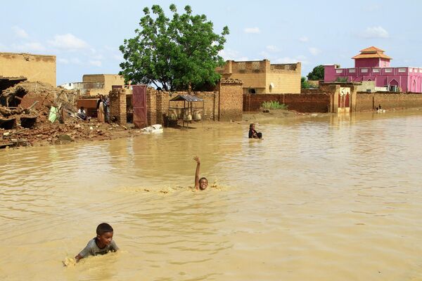 洪水で冠水した街の中を泳ぐ子どもたち（スーダン・ハルツーム、22日） - Sputnik 日本