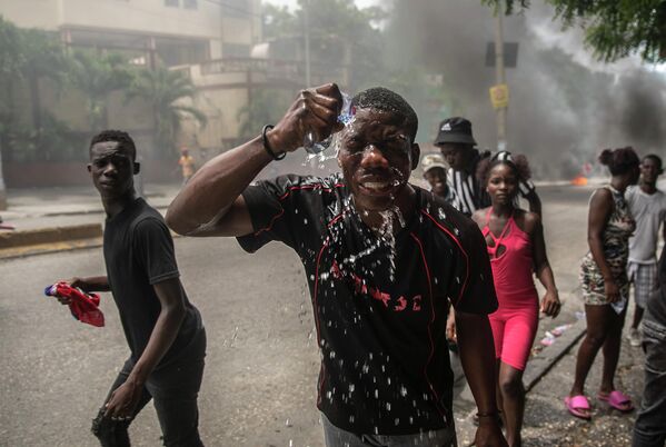 アリエル・アンリ首相の退陣を求めるデモで、警察から発催涙ガスをかけられ顔に水をかける抗議者ハイチ・ポルトープランス、29日） - Sputnik 日本