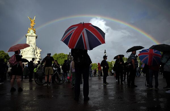 クイーンビクトリア記念碑のそばで、ユニオンジャック柄の傘をさす人（英ロンドン、8日） - Sputnik 日本