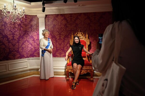 マダム・タッソー蝋人形館で、エリザベス女王の蝋人形の横に並ぶ女性（中国・北京、9日） - Sputnik 日本