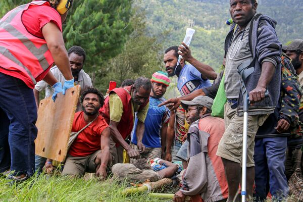 負傷した村人をヘリコプターへ運ぶ準備をする人々（パプアニューギニア・モロベ州、11日） - Sputnik 日本