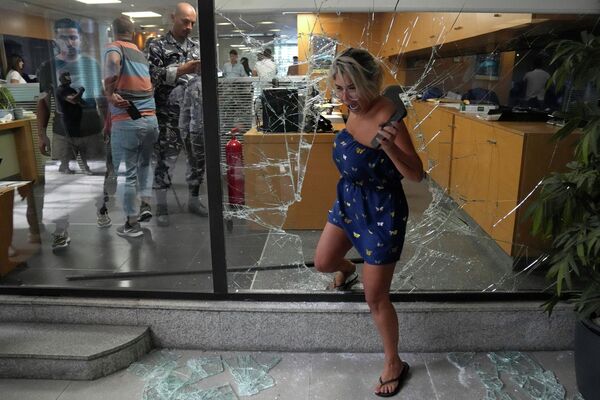 銀行強盗によって割られた窓から外へ出る職員（レバノン・ベイルート、14日） - Sputnik 日本
